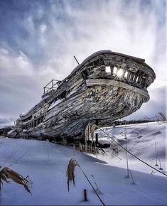 an old ship sitting on top of snow covered ground