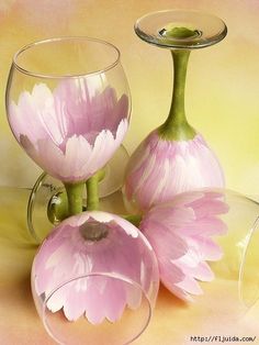 three wine glasses with pink flowers in them on a yellow and pink background, one is filled with water