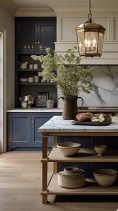 a kitchen with blue cabinets and marble counter tops, an island in the middle has plates on it