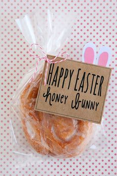 a bagel wrapped in plastic on top of a pink polka dot tablecloth with a sign that says happy easter honey bunny