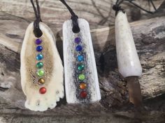 three necklaces with different colored beads hanging from them on a piece of driftwood