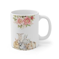 a white coffee mug with an image of rabbits and flowers on the side, in front of