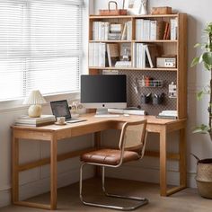 a computer desk with a laptop on top of it next to a book shelf filled with books