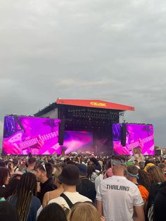 a large group of people standing in front of a stage with purple lights on it