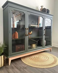 a green china cabinet with glass doors on the top and bottom, next to a potted plant