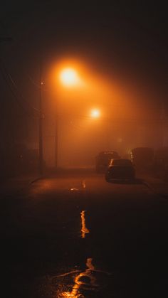 cars driving down the road at night with street lights in the foggy sky above