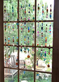 a window with beads hanging from it's side and a bench in the background