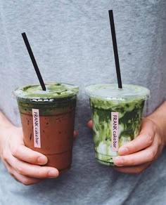 two people holding up cups with drinks in them and straws sticking out of the lids