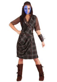 a woman in a plaid dress and brown boots posing for the camera with her hands on her hips