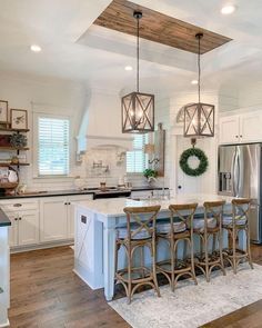 a kitchen with white cabinets and an island in front of the refrigerator, surrounded by stools