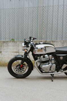 a black and silver motorcycle parked in front of a building with a chain link fence