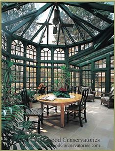 the inside of a glass house with tables and chairs in front of it, surrounded by greenery