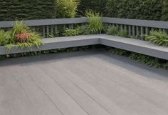 an outdoor seating area with plants on the wall and wood flooring in front of it