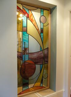 a stained glass window in the corner of a room with white walls and wood flooring