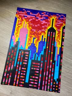 a piece of art made out of legos on a wooden floor with buildings in the background