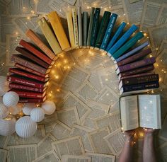 a person holding a book in front of a circle of books with lights on them