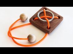 an orange string is attached to a wooden block with two balls on it and one ball in the middle