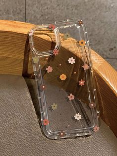 an iphone case with flowers on it sitting on a wooden chair in front of a wall