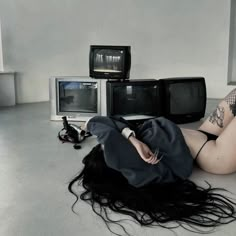 a woman laying on the floor in front of three tvs and two monitors,