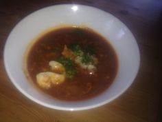 a white bowl filled with soup on top of a wooden table