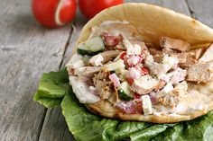 an open pita sandwich with meat, lettuce and tomatoes