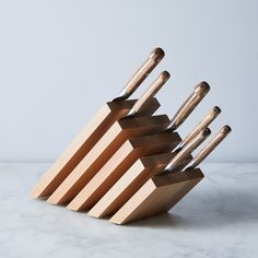 a set of wooden utensils sitting on top of a marble counter next to a white wall