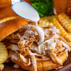 a pulled pork sandwich is being drizzled with white sauce