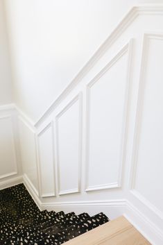 an empty room with white walls and wood flooring on the bottom half of the wall