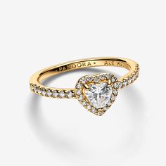 Radiate love in our Elevated Heart Ring featuring a symbolic heart-shaped clear cubic zirconia, set in a 14k gold plating with a pavé halo. Its raised stone and claw setting highlight the eye-catching centre, while half of the ring shank is adorned with pavé. Perfect for adding a touch of love to any outfit, this ring captures the essence of heartfelt connections. - Pandora Elevated Heart Ring - 14k Gold-plated unique metal blend / Cubic Zirconia / Clear - Sz. 7.5 Unique Promise Rings For Her Gold, Pandora Gold Heart Ring, Pandora Gold Jewelry, Gold Pandora Ring, Promise Rings For Her Gold, Pandora Gold Rings, Gold Promise Rings For Her, Pandora Elevated Heart Ring, Gold Pandora Rings