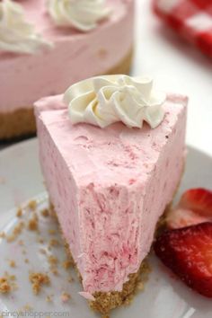 two slices of strawberry cheesecake with whipped cream on top and strawberries in the background