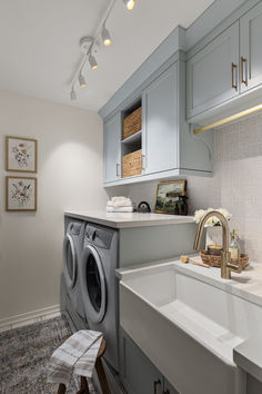 a washer and dryer in a small room with grey cabinets on the walls