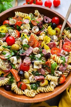 a bowl filled with pasta salad next to tomatoes