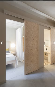 an open door leading to a bedroom with a bed in the background and two mirrors on the wall