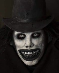 a man in a top hat and face paint is wearing a black suit with white teeth