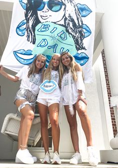 three girls are posing in front of a banner