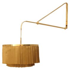 a gold colored lamp with pleated shades on the bottom and an arm that is attached to it