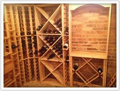 a wine rack with many bottles in it next to a brick wall and flooring