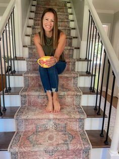 a woman sitting on the stairs holding a bowl of fruit