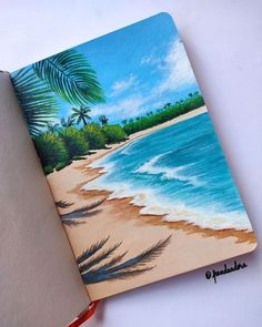 an open notebook with a painting of a beach and palm trees