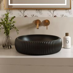 a bathroom sink with a round black bowl on the counter and a mirror above it