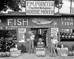 an old photo of people standing in front of a house mover store selling fresh produce