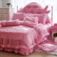 a pink bed with ruffled bedspread and pillows