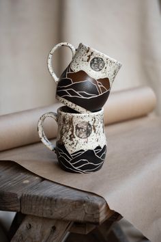 two coffee cups sitting on top of a wooden table