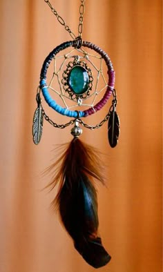 a dream catcher with feathers and beads hanging from it's side on a wall