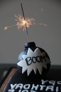 a black and white birthday cake with a sparkler in the top that says boom