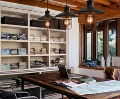 a desk with a laptop on top of it in front of a book shelf filled with books