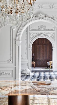 an ornate room with chandelier, marble flooring and white walls in the background