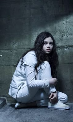 a woman sitting on the ground in white clothes