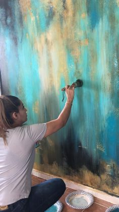 a woman painting a wall with blue and green paint