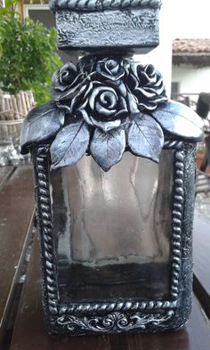 an old fashioned glass bottle with flowers on the top is sitting on a wooden table